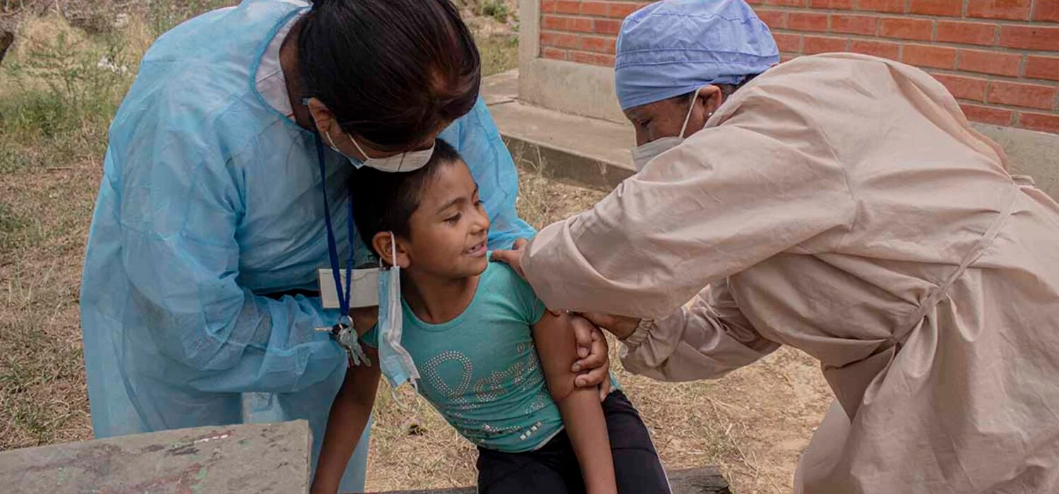 health worker giving vaccination to a young patient being held by another health worker